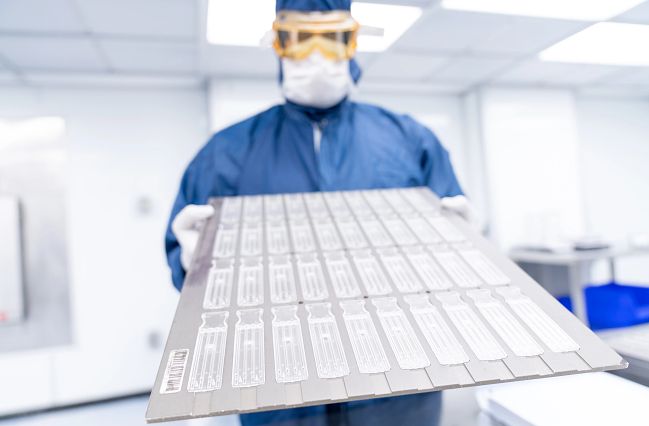 Two scientists holding up and looking at a single Endosafe Cartridge