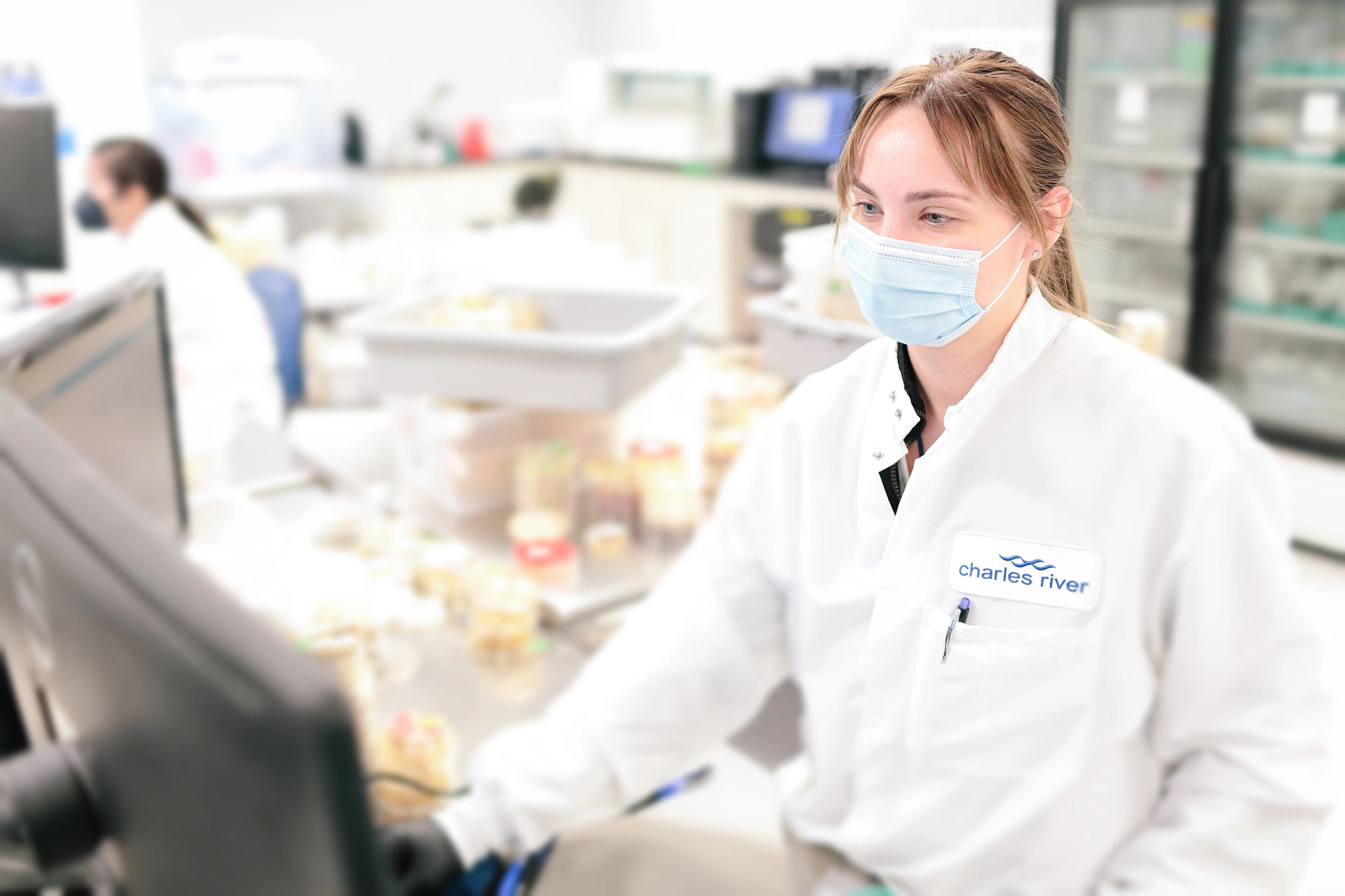 Charles River scientist wearing a lab coat and mask in a laboratory.