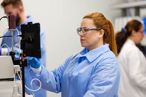 Scientist in PPE working at computer in lab