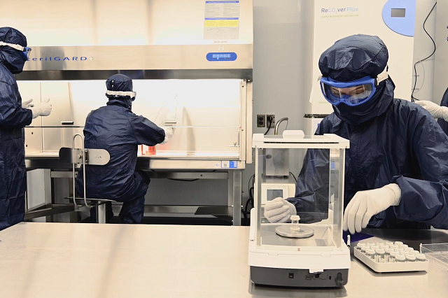 Scientists wearing full PPE in a cleanroom conducting Cell Therapy GMP Manufacturing Services.
