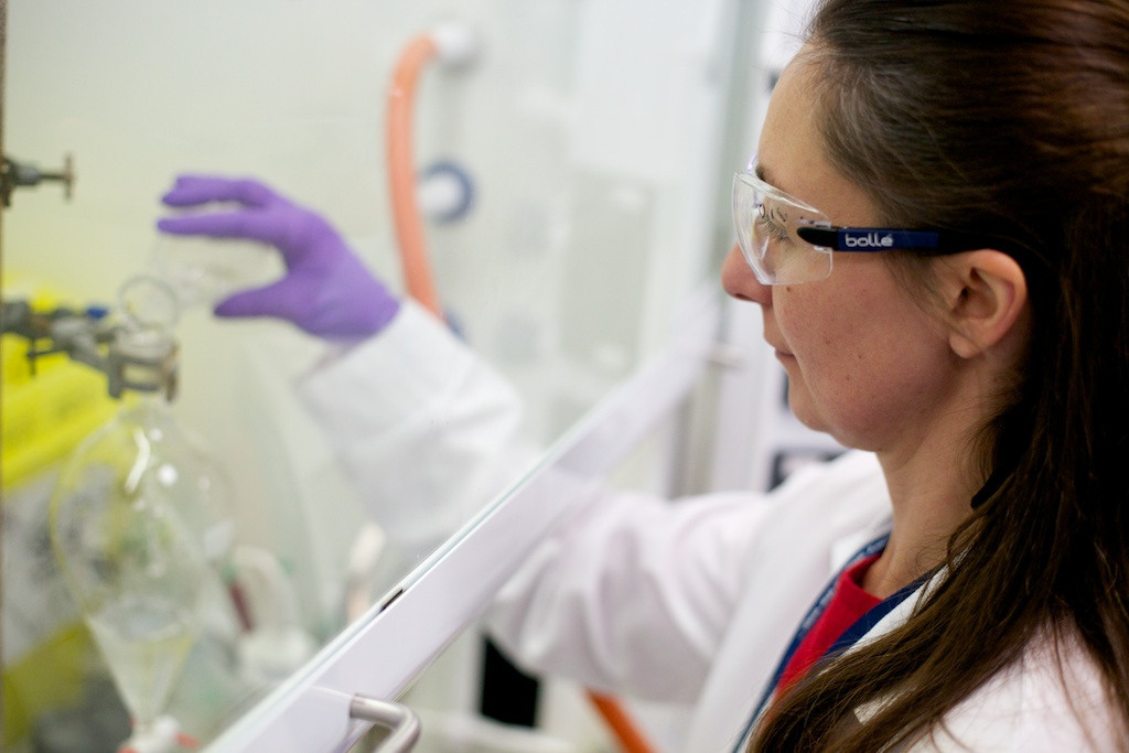 drug discovery scientist pouring liquid from flask in flowhood