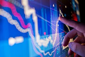 hand pointing at trending data chart on a computer screen