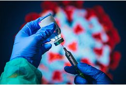 gloved hands using a syringe to extract liquid from a vial
