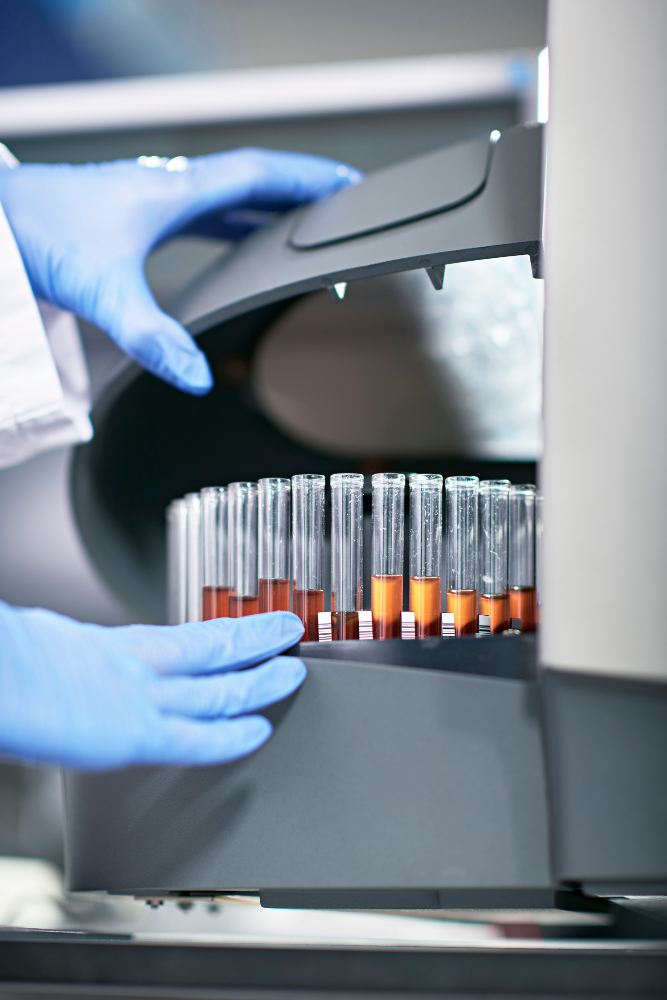 gloved hands working at a machine with test tubes on it for flow cytometry