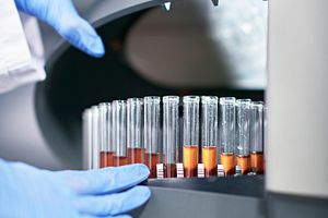 gloved hands working at a machine with test tubes on it for flow cytometry