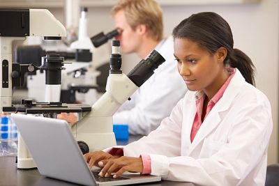 Male and female scientists using microscopes in laboratory