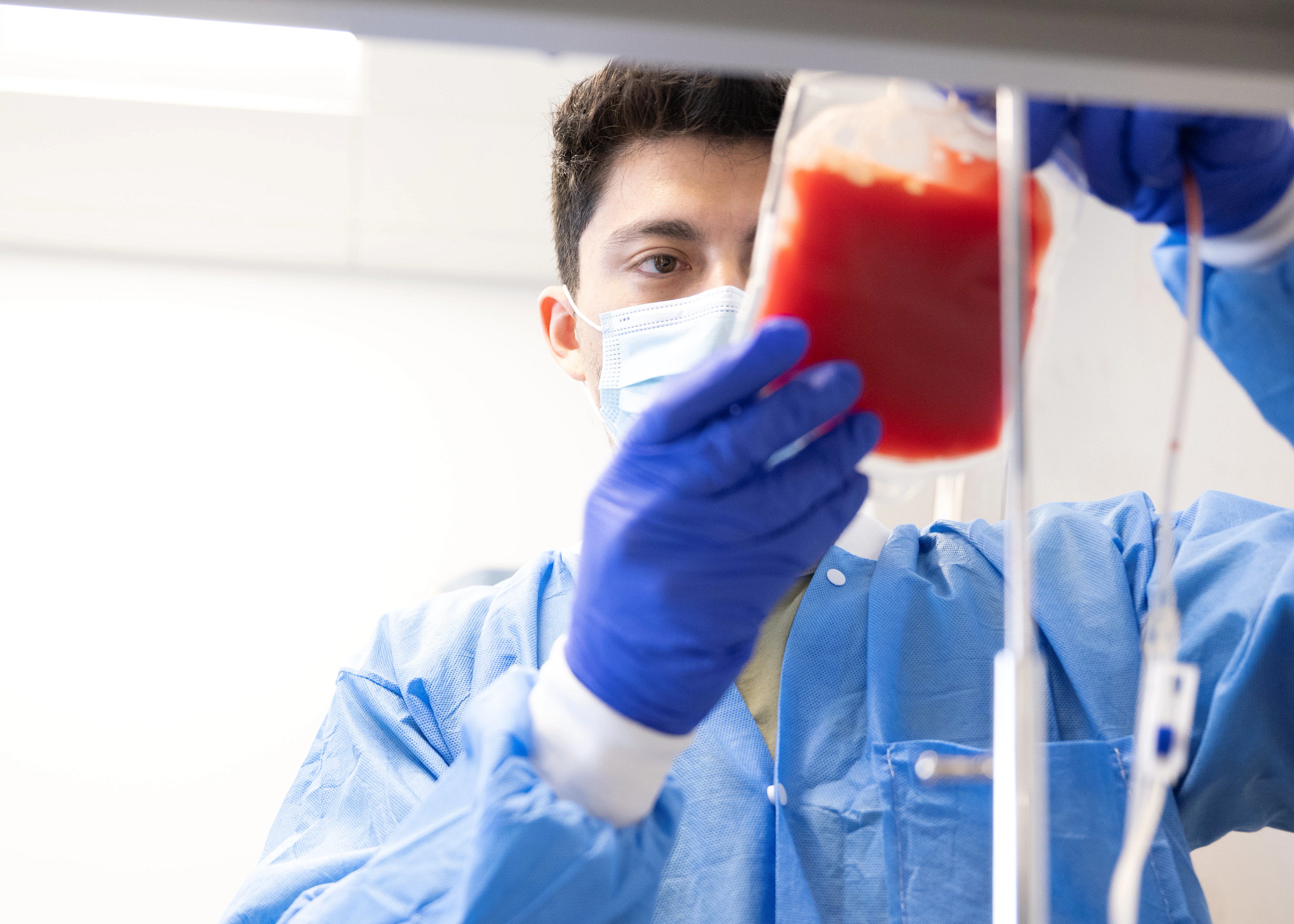 male technician in mask and gown holding a leukopak