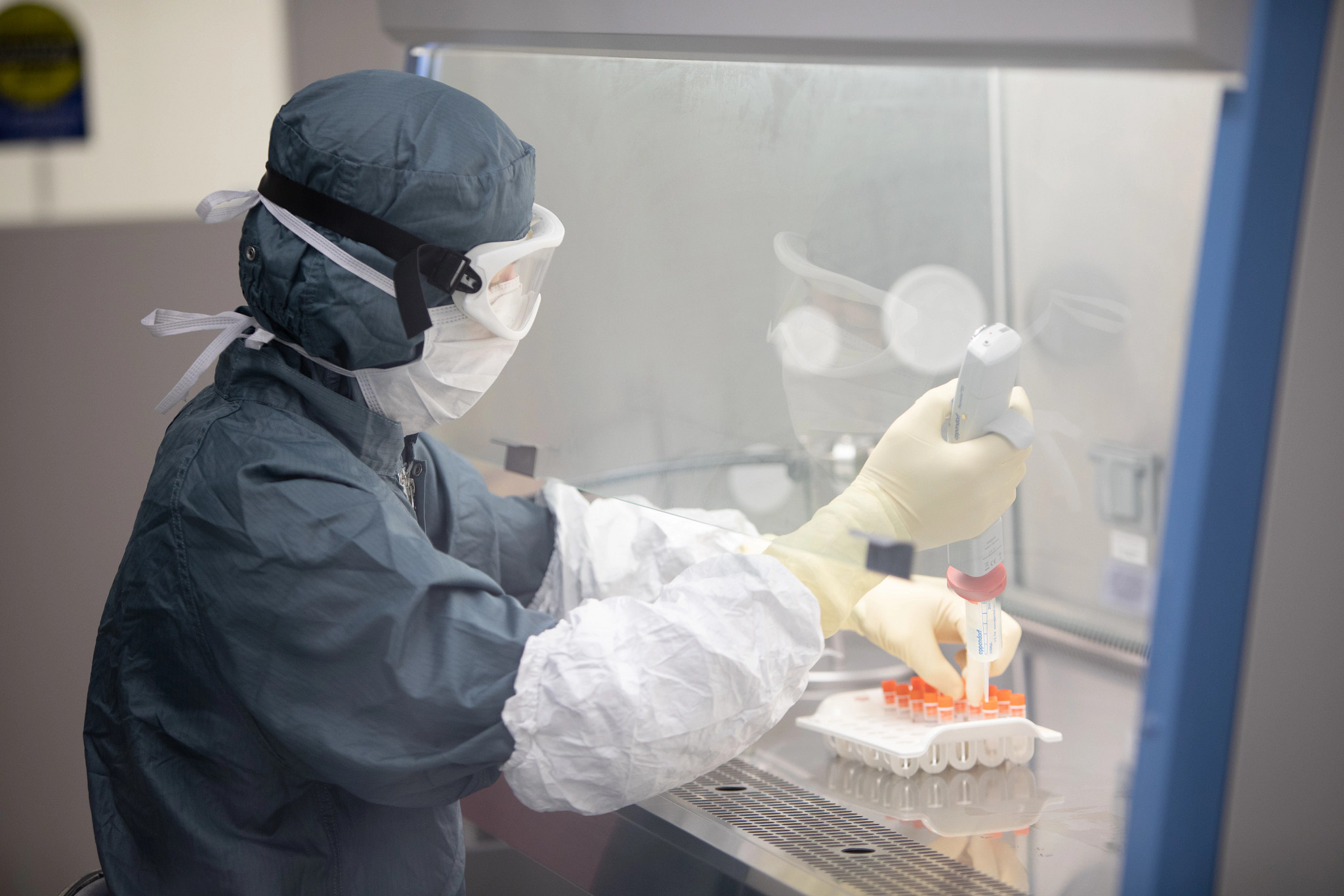 Technician wearing PPE and working in a lab.