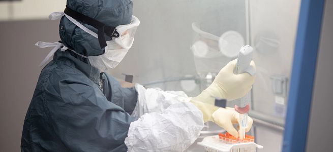 Technician wearing PPE and working in a lab.
