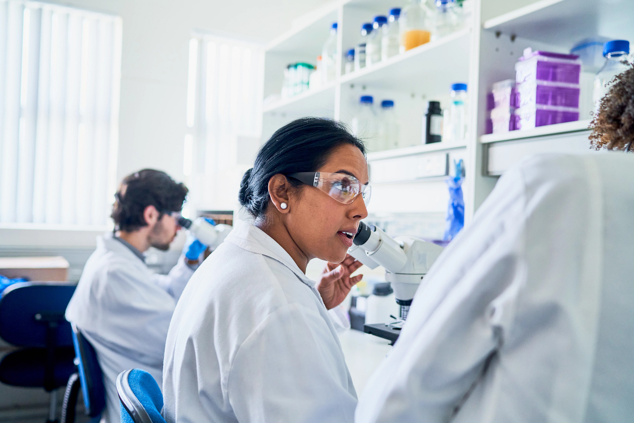 Researchers in a laboratory working at microscopes and analyzing samples as part of molecular biology services in a specialist lab.