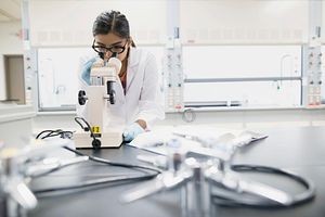 Scientist in the Boisbriand, Canada Facility looking through a microscope.