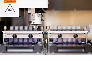 Scientist in a lab coat looking through a microscope.