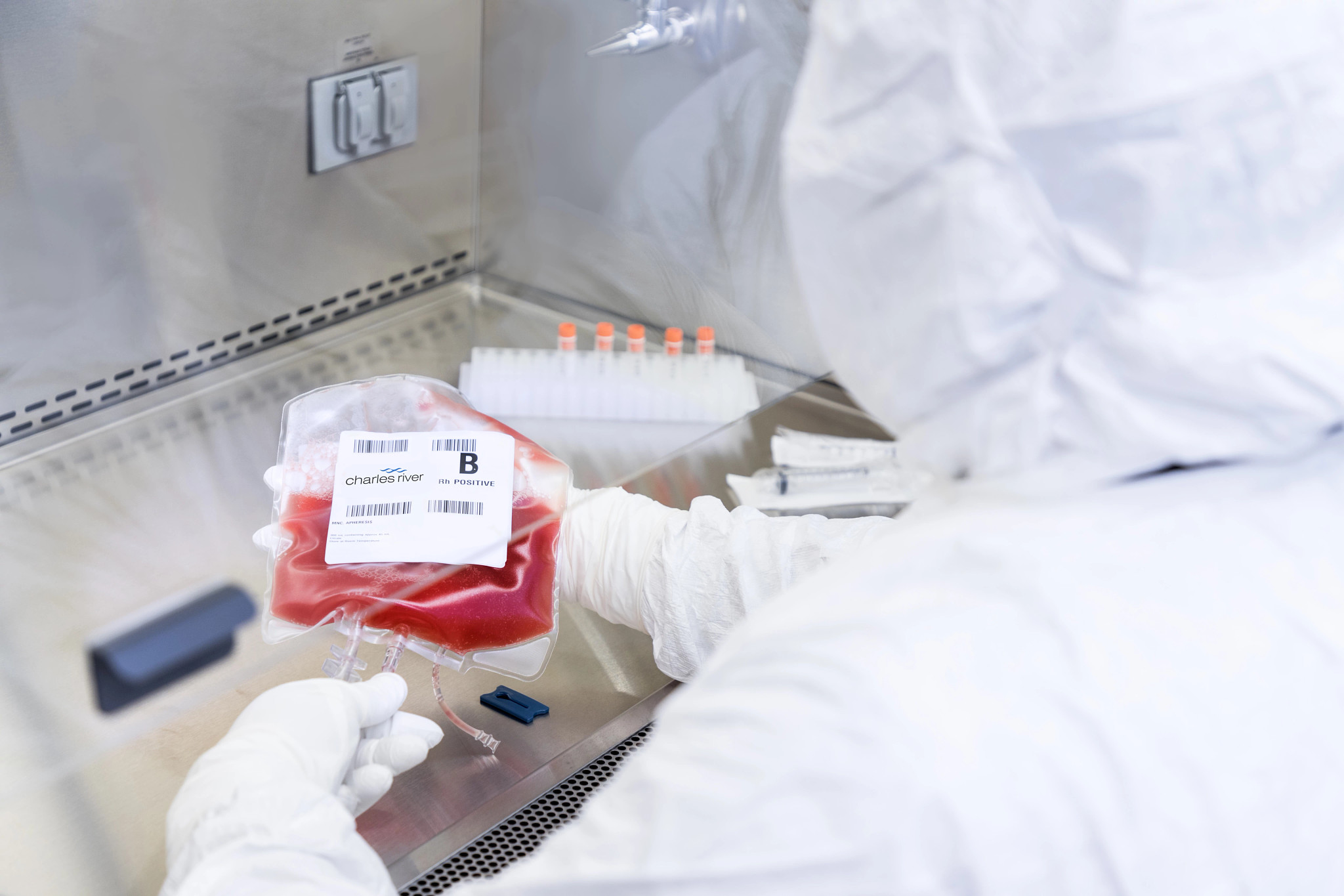 lab technician in sterile gowning working with a leukopak