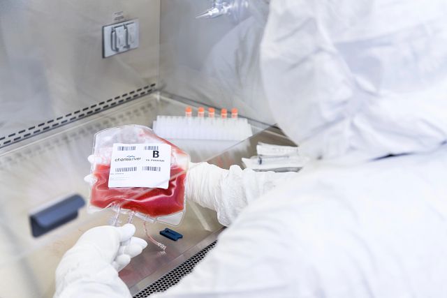lab technician in sterile gowning working with a leukopak