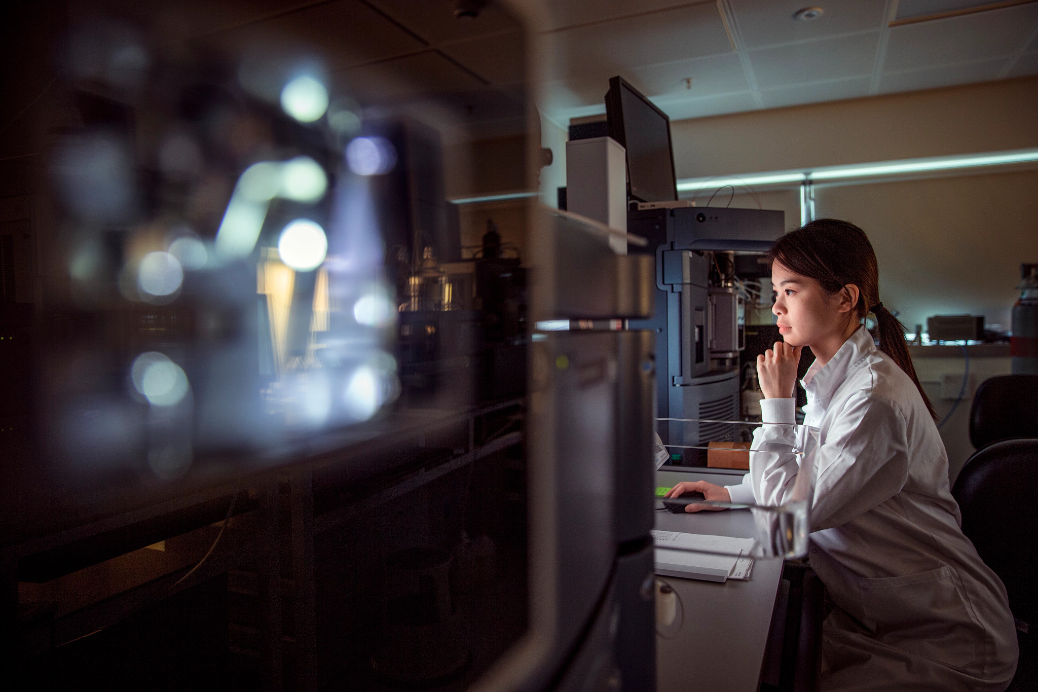 Photo of a female scientist working on a computer in a lab.