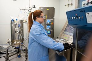 Person in a blue lab coat operates equipment in a cleanroom operates a 50L bioreactor at Charles River’s Viral Vector CDMO Center of Excellence