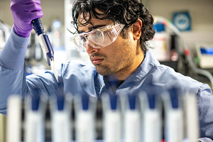lab tech wearing PPE holding a pipette