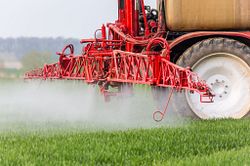 Red tractor fertilizing a field.