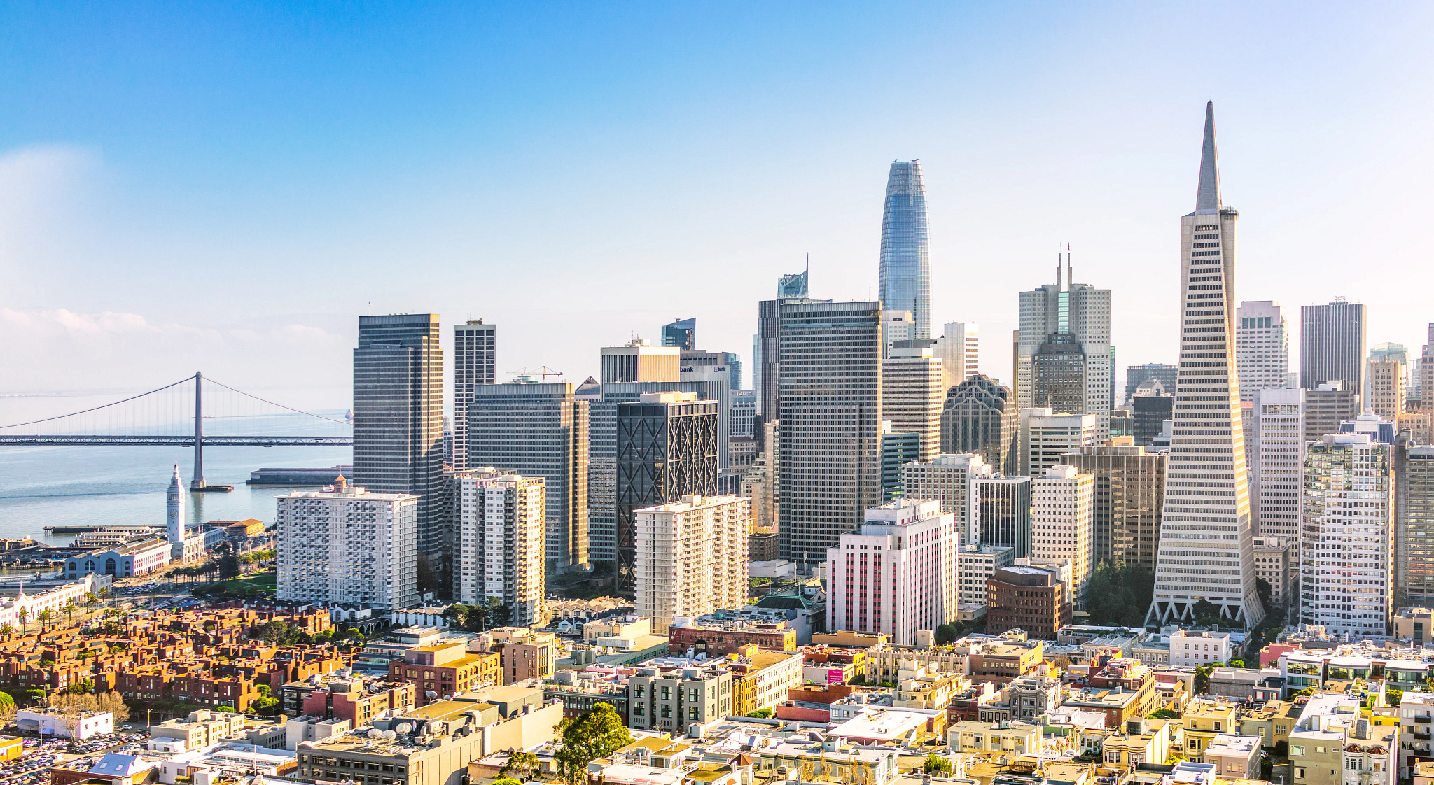 Photo of the San Francisco skyline, with the Golden Gate Bridge in the background on a sunny day.