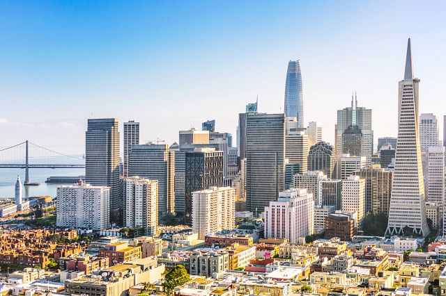 Photo of the San Francisco skyline, with the Golden Gate Bridge in the background on a sunny day.
