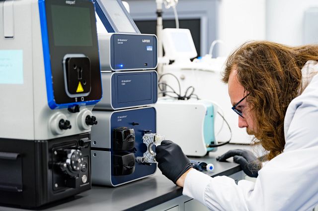 Scientist wearing a lab coat and gloves, working on a cell therapy device.