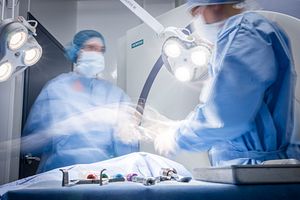 Surgeons operating on a patient, moving quickly.