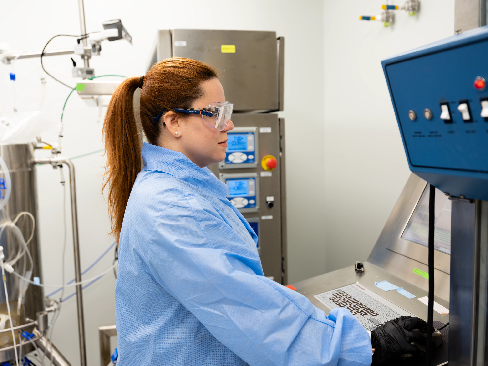 Scientist wearing PPE and working at a computer in a lab.