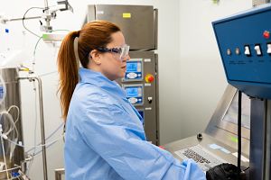 Scientist wearing PPE and working at a computer in a lab.