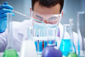 Investigator checking test tubes, Man wears protective goggles, scientist pipetting samples