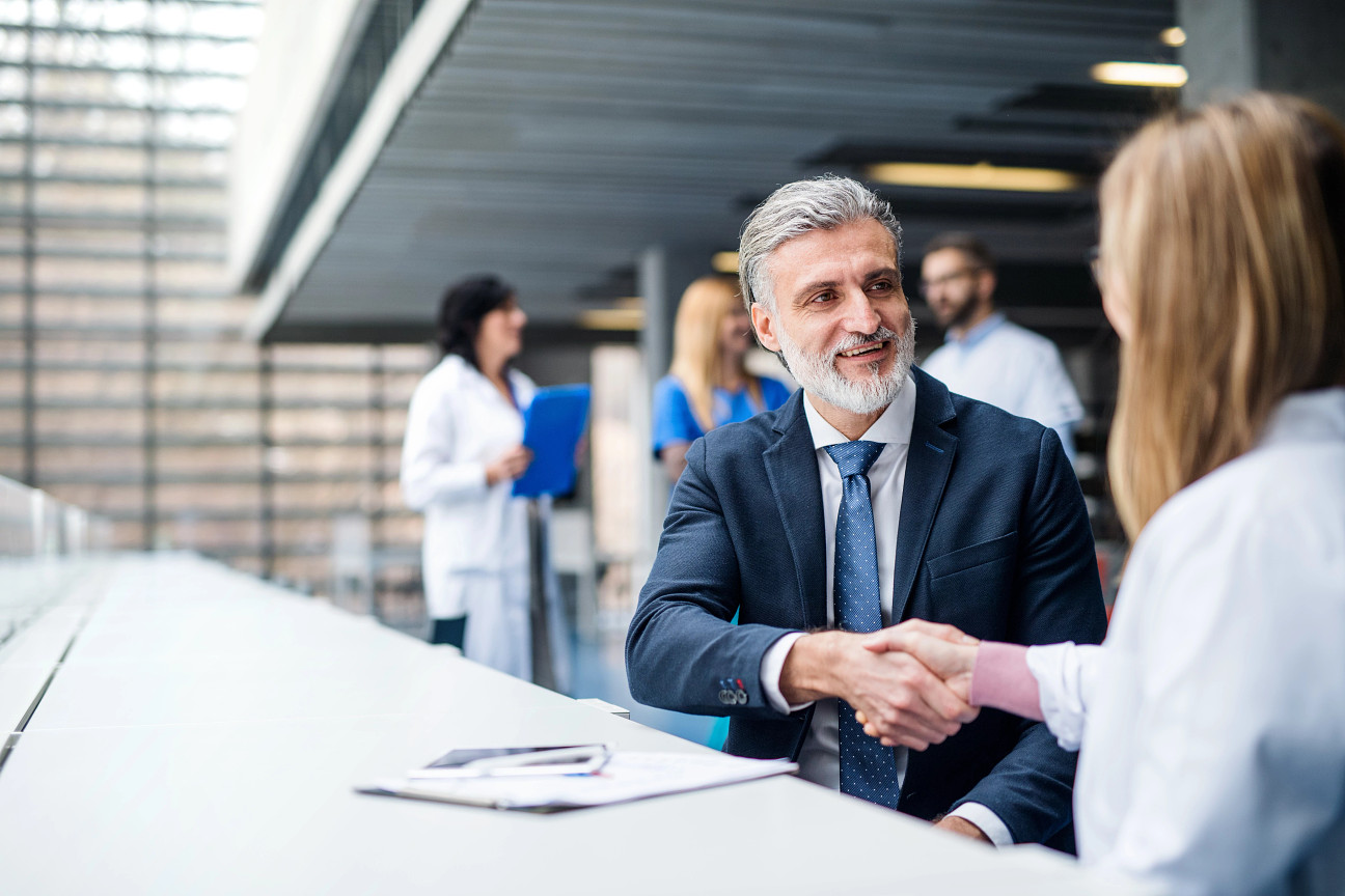 Man with a beard in a suit shaking hands with a woman at the APAC Biomanufacturing Leadership Summit