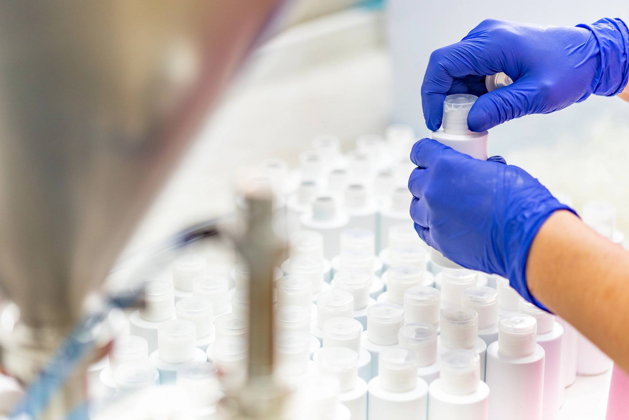Photo of someone wearing rubber gloves tightening the lit of a cosmetics bottle.
