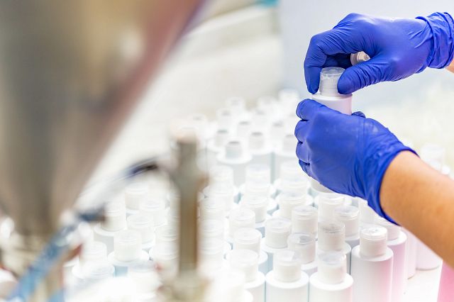 Photo of someone wearing rubber gloves tightening the lit of a cosmetics bottle.